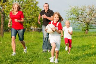 Family-running-with-soccer-ball